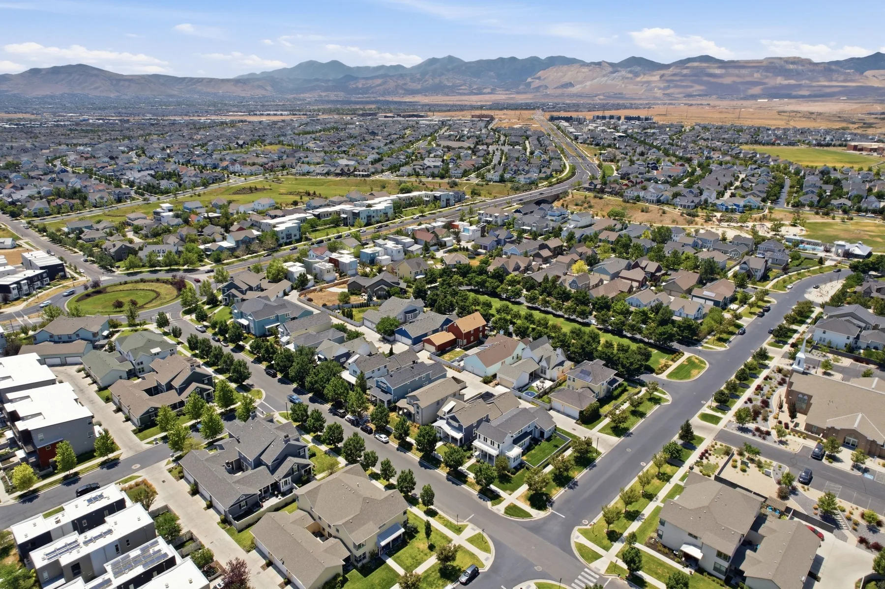 Aerial view of Daybreak homes, parks, and streets with mountains beyond