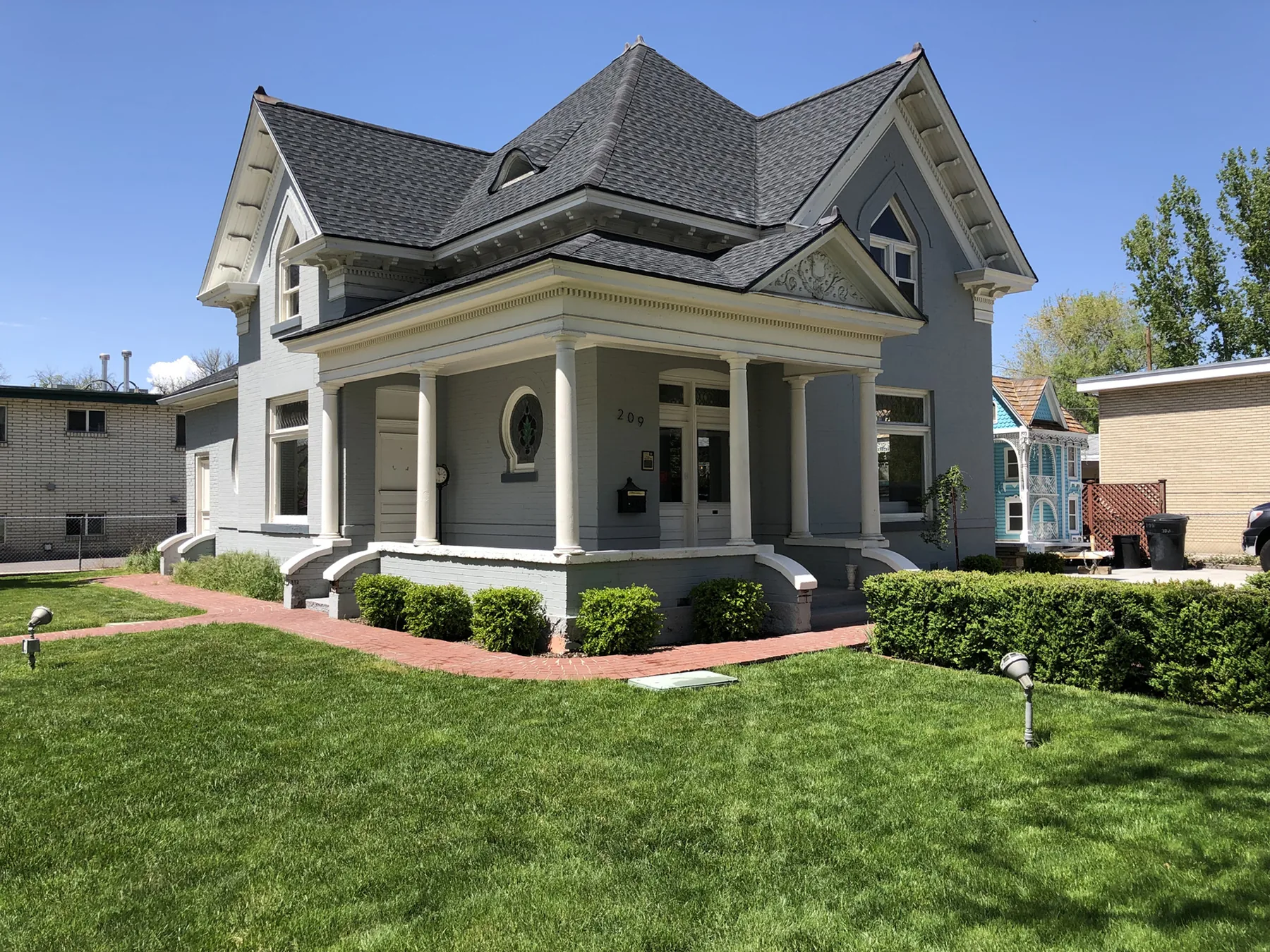 Gray Victorian-era building with an ornate porch and steep gabled roof