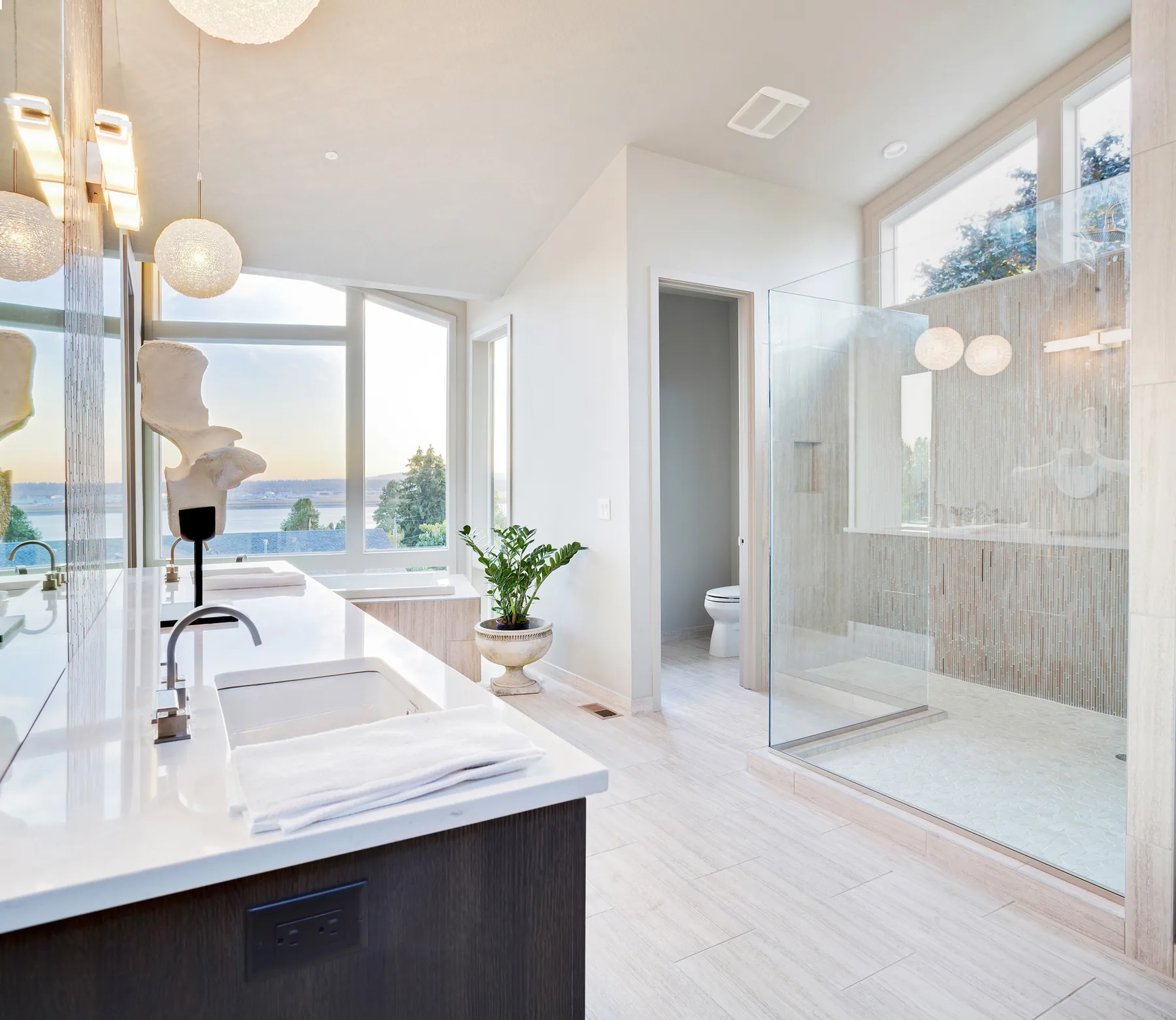 Light-filled primary bathroom with a glass shower and expansive windows