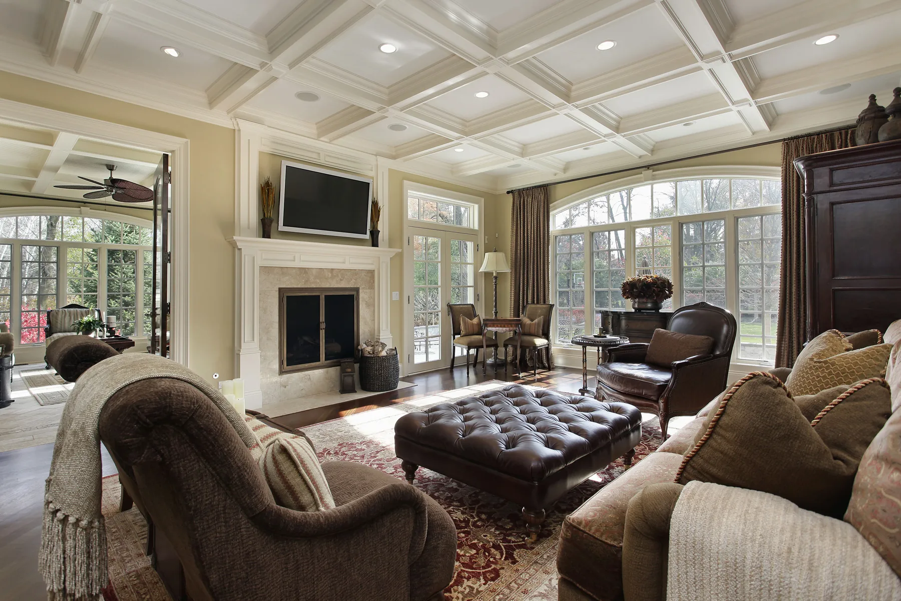 Traditional living room with a fireplace, coffered ceiling, and large garden windows