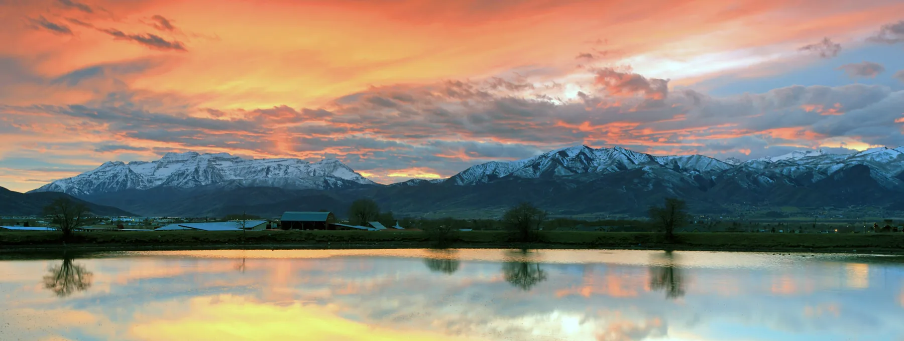 Snow-covered Wasatch Mountains reflected in water at sunset